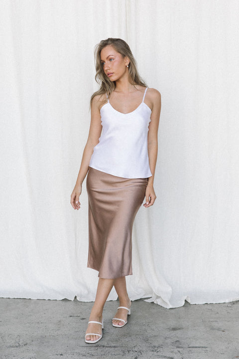 Woman wearing white silk camisole and taupe silk slip skirt