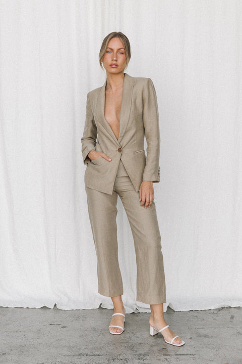 Model wearing a taupe linen blazer and trouser posing in a studio